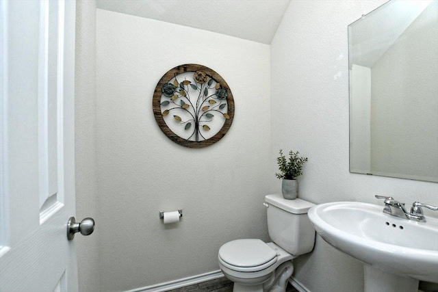 bathroom featuring a sink, baseboards, toilet, and a textured wall