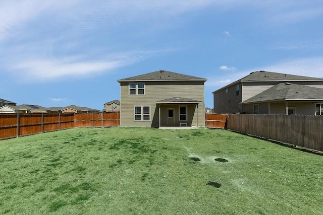 rear view of house featuring a yard and a fenced backyard