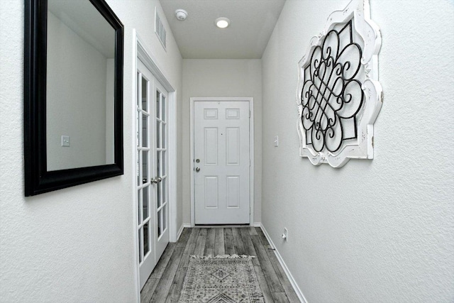 entryway with wood finished floors, visible vents, baseboards, french doors, and a textured wall