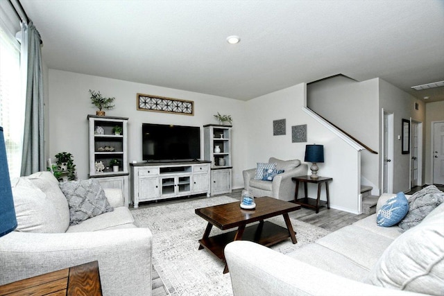 living area with stairway, visible vents, and wood finished floors