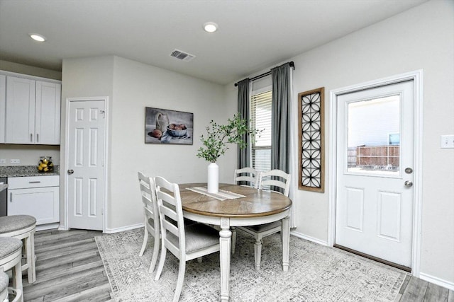 dining area featuring light wood finished floors, visible vents, and baseboards