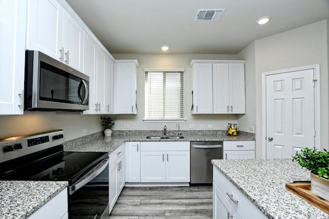 kitchen with visible vents, light wood finished floors, a sink, white cabinets, and appliances with stainless steel finishes