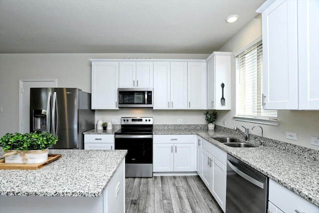 kitchen featuring a sink, stainless steel appliances, white cabinets, and light wood finished floors