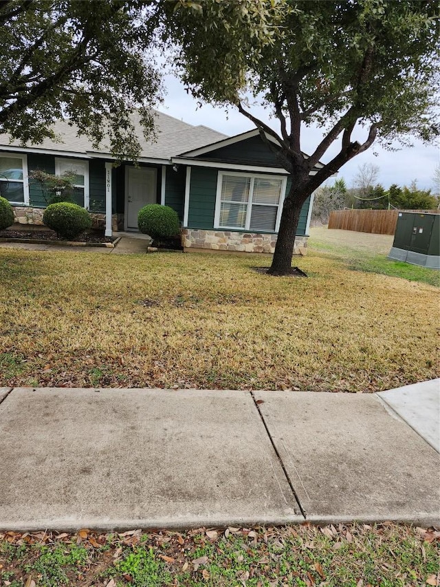 view of front of house featuring a front lawn, fence, and stone siding