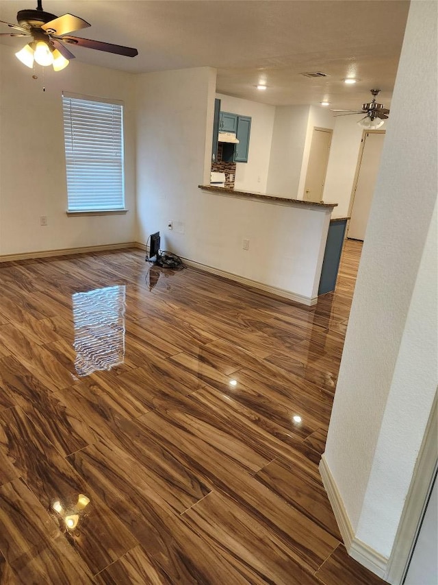 unfurnished living room with baseboards, wood finished floors, and a ceiling fan