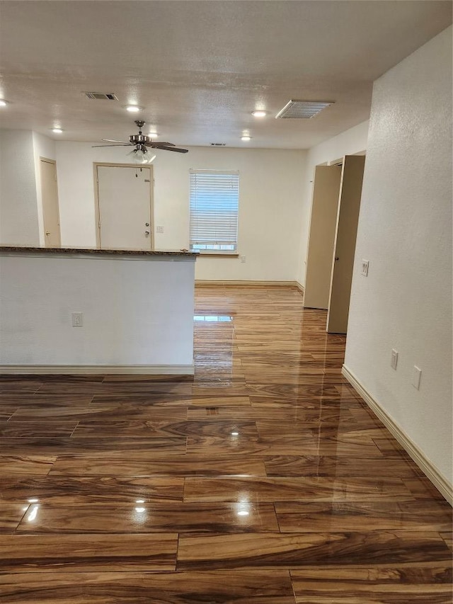 empty room featuring visible vents, wood finished floors, baseboards, and ceiling fan