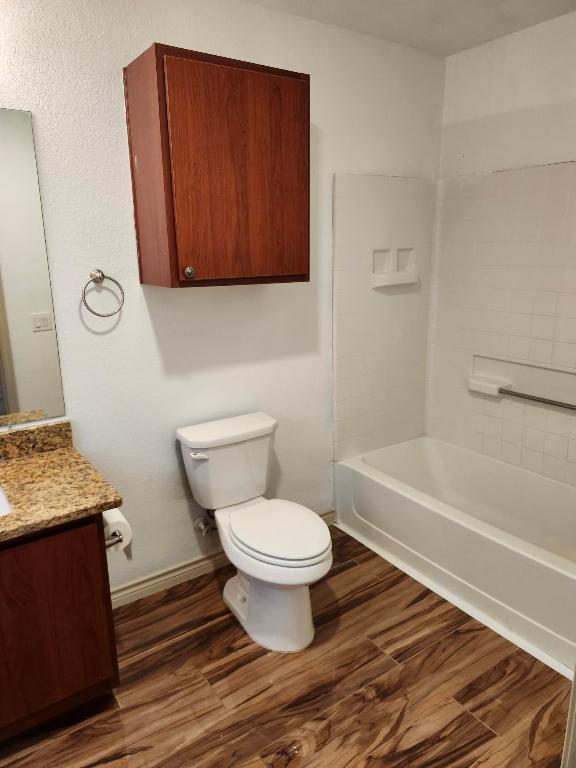 full bathroom with toilet, vanity, wood finished floors, and baseboards