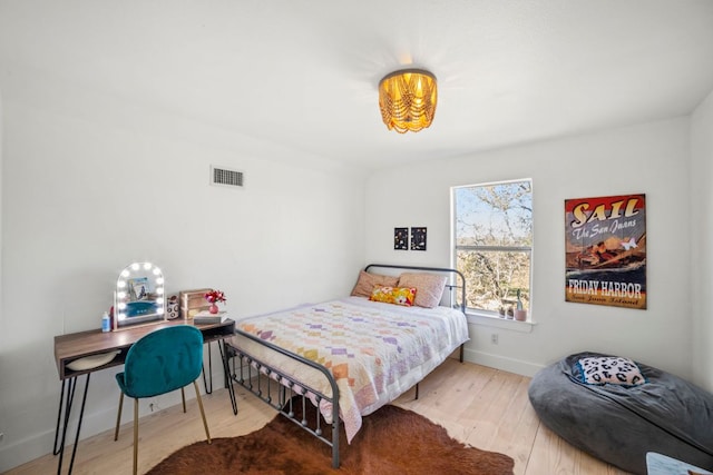 bedroom with wood finished floors, visible vents, and baseboards