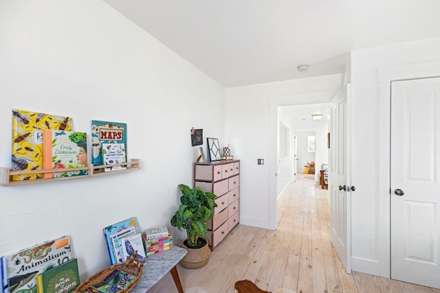 corridor featuring light wood finished floors and baseboards