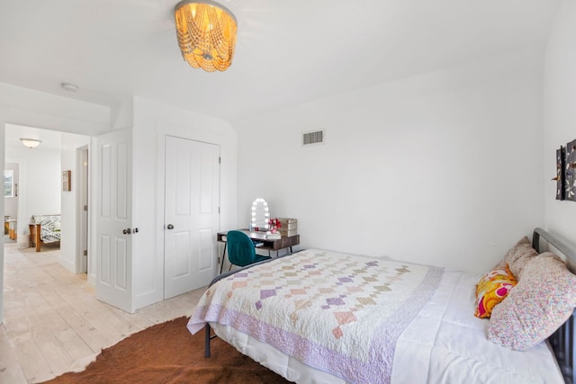 bedroom featuring wood finished floors, visible vents, and a closet