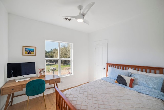 bedroom featuring a ceiling fan, wood finished floors, visible vents, and baseboards