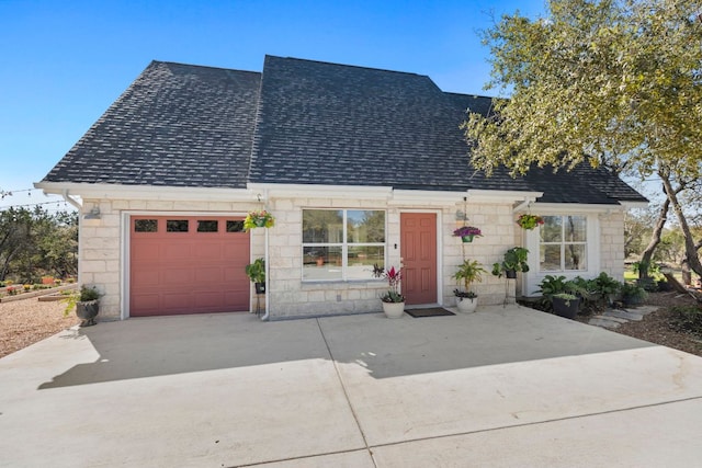 view of front of house featuring stone siding, an attached garage, concrete driveway, and roof with shingles