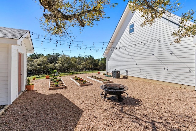 view of yard with central air condition unit, an outdoor fire pit, and a vegetable garden