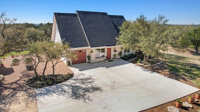 view of front of property featuring roof with shingles and concrete driveway