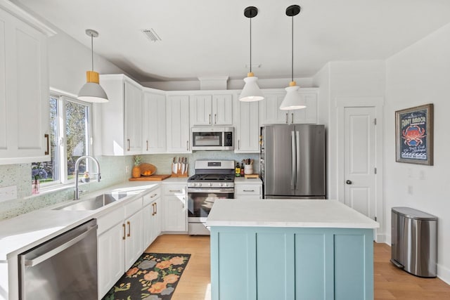 kitchen featuring visible vents, a sink, stainless steel appliances, white cabinetry, and light wood-type flooring