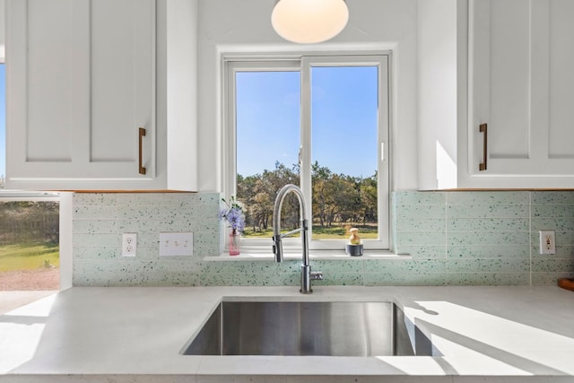 kitchen featuring white cabinetry, light countertops, tasteful backsplash, and a sink