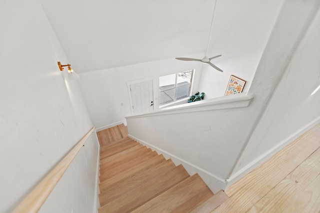 stairs featuring ceiling fan, wood finished floors, and vaulted ceiling