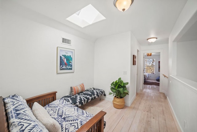 interior space with visible vents, light wood-style flooring, a skylight, and baseboards