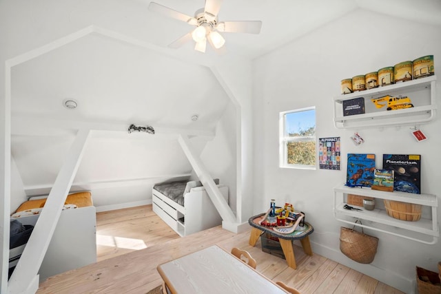 interior space with lofted ceiling, wood finished floors, baseboards, and ceiling fan