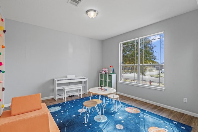 recreation room featuring wood finished floors, visible vents, and baseboards