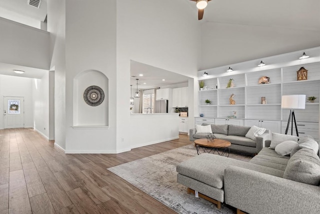 living room with baseboards, a high ceiling, ceiling fan, and wood finished floors