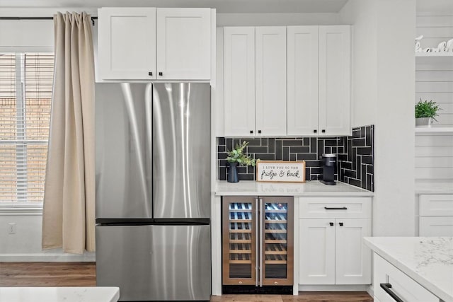 18516 Silent Water Way, Pflugerville, TX 78660 - kitchen with freestanding refrigerator, wine cooler, white cabinets, decorative backsplash, and wood finished floors