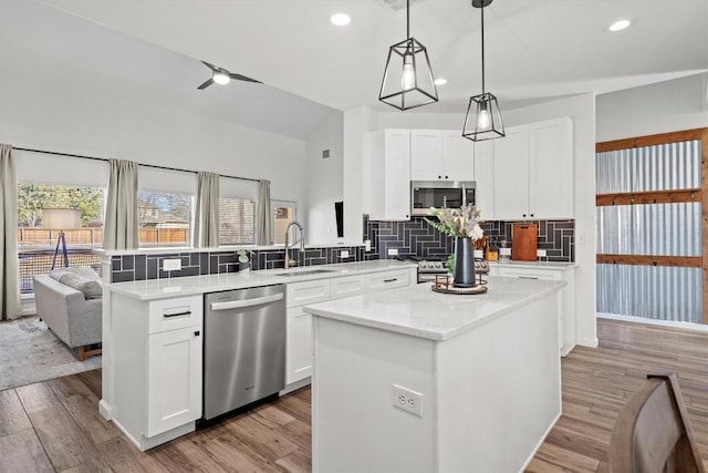 kitchen with light wood finished floors, a kitchen island, decorative backsplash, appliances with stainless steel finishes, and a peninsula