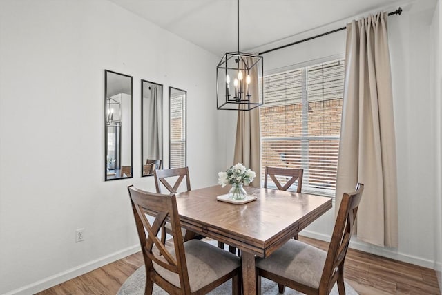 dining area featuring a notable chandelier, baseboards, and light wood-style floors