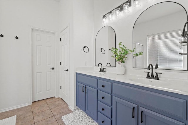 bathroom with tile patterned flooring, double vanity, baseboards, and a sink