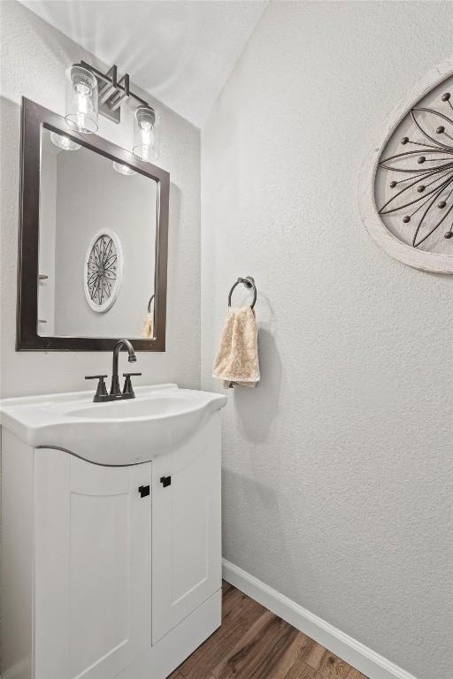 18516 Silent Water Way, Pflugerville, TX 78660 - bathroom with wood finished floors, vanity, baseboards, and a textured wall