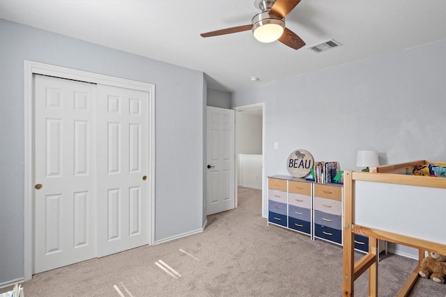 carpeted bedroom featuring visible vents, a closet, and a ceiling fan