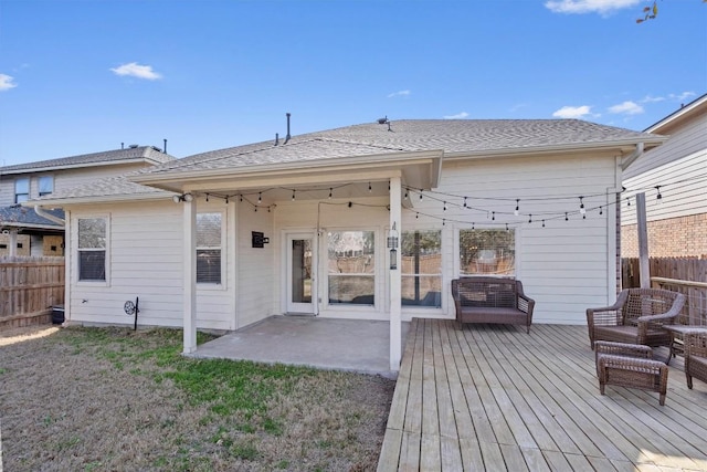 back of property featuring a wooden deck, roof with shingles, and fence