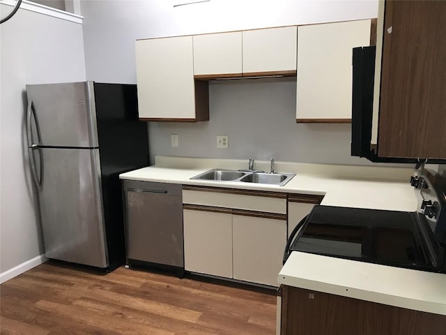 kitchen featuring appliances with stainless steel finishes, light countertops, light wood-style floors, and a sink