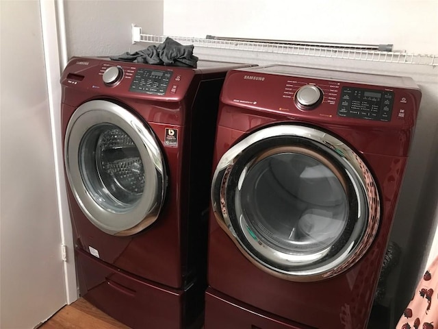 laundry area with laundry area, washer and dryer, and wood finished floors