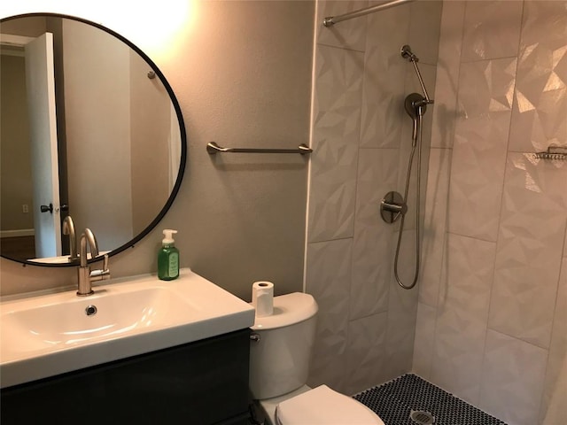 bathroom featuring vanity, toilet, and a tile shower