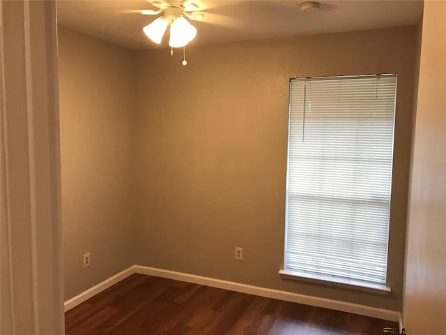 unfurnished room with dark wood finished floors, a ceiling fan, and baseboards