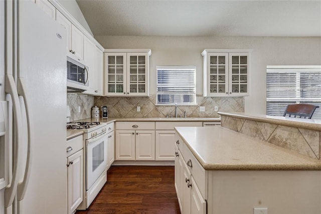 kitchen featuring a sink, tasteful backsplash, dark wood-style floors, white appliances, and white cabinets