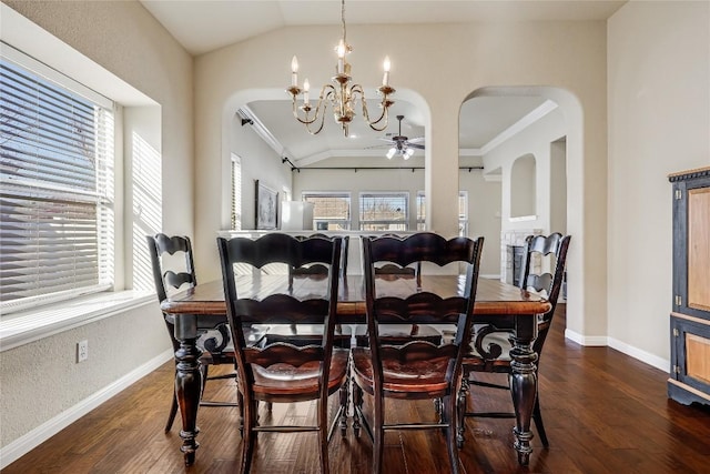 dining area with ceiling fan with notable chandelier, arched walkways, dark wood-style floors, and vaulted ceiling