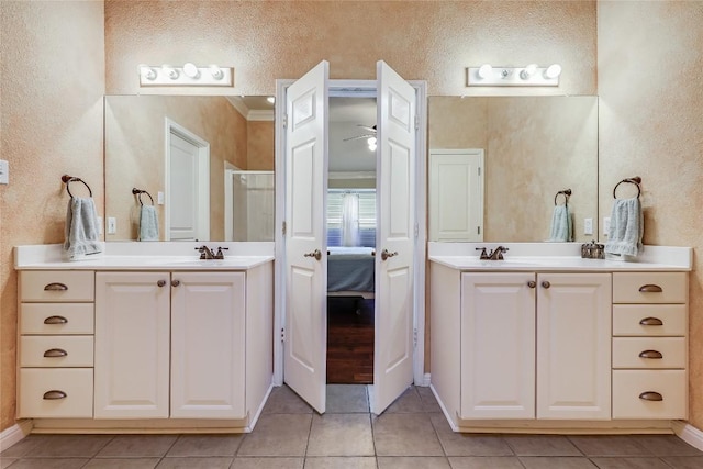 bathroom with a shower stall, two vanities, and tile patterned floors