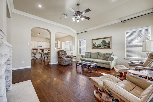 living area with visible vents, arched walkways, dark wood finished floors, and a ceiling fan