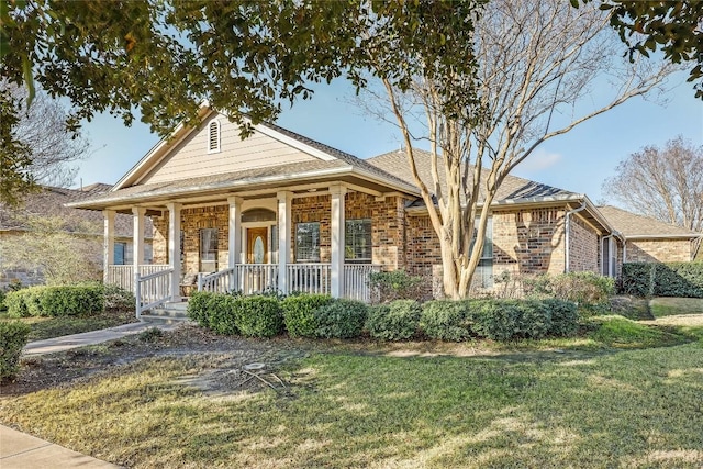 view of front of home with brick siding, covered porch, a front yard, and a shingled roof