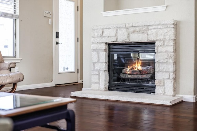 living room featuring a healthy amount of sunlight, a fireplace, baseboards, and wood finished floors