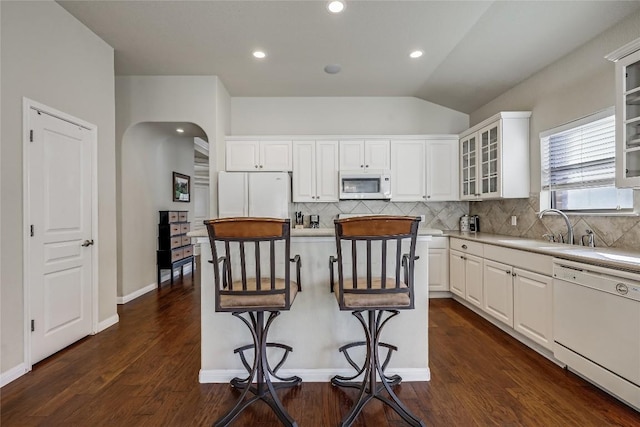 kitchen with white appliances, a breakfast bar area, a sink, light countertops, and vaulted ceiling