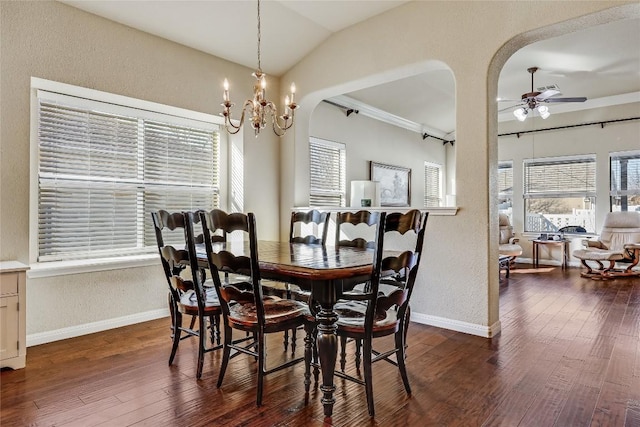 dining room with baseboards, arched walkways, dark wood-type flooring, vaulted ceiling, and ceiling fan with notable chandelier