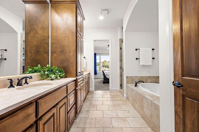 full bath featuring tile patterned floors, visible vents, a sink, double vanity, and a relaxing tiled tub