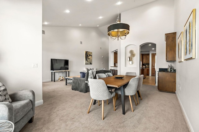 dining area featuring baseboards, light carpet, recessed lighting, arched walkways, and high vaulted ceiling