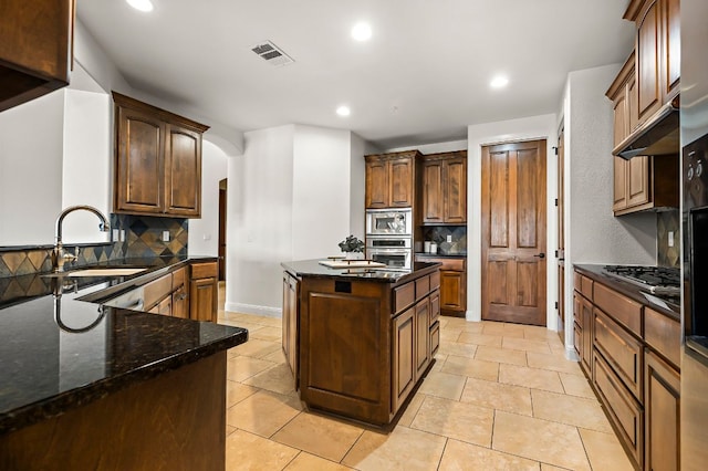 kitchen with visible vents, arched walkways, a sink, decorative backsplash, and appliances with stainless steel finishes