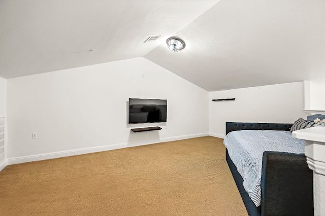 unfurnished bedroom featuring light colored carpet, lofted ceiling, baseboards, and visible vents