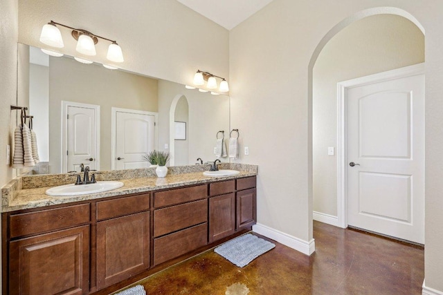 full bathroom featuring a sink, baseboards, finished concrete floors, and double vanity