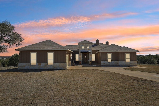 view of front of house with stone siding, board and batten siding, and a yard